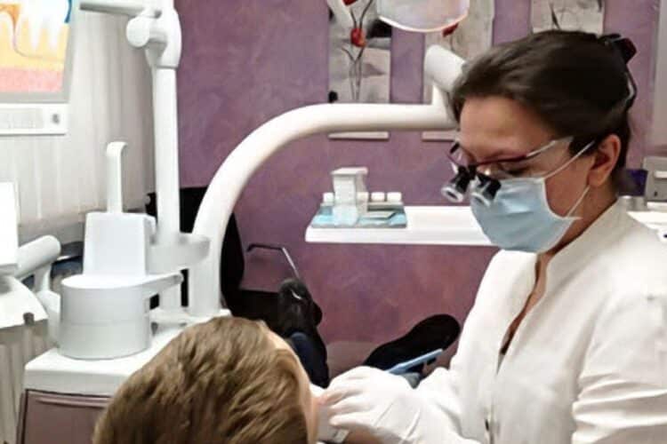 Eine Frau wird in einer Zahnarztpraxis kinderzahnmedizinisch behandelt.