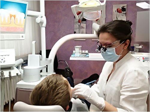 Eine Frau sitzt für einen Praxiseingriff auf einem Zahnarztstuhl.